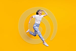 Full size profile side photo of young girl happy positive smile jump up go walk run look ahead isolated over yellow