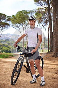 Full speed ahead. a cyclist standing with his bike outdoors.