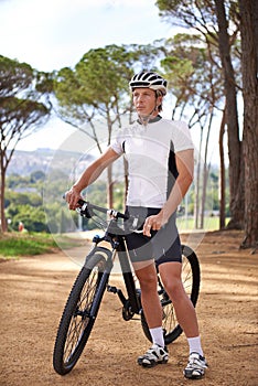 Full speed ahead. a cyclist standing with his bike outdoors.