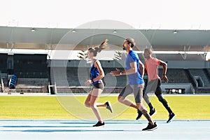 Full speed ahead. Full length shot of three young athletes running along the track together.