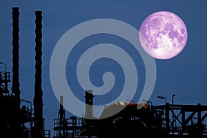 Full Strawberry Moon back on silhouette refinery on night sky