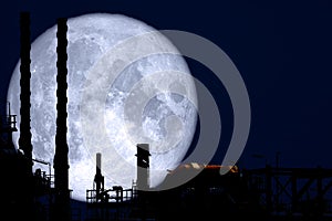 Full Strawberry Moon back on silhouette refinery on night sky