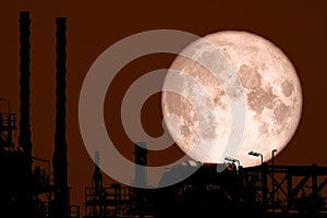 Full Strawberry Moon back on silhouette refinery on night sky