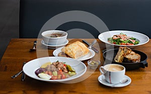 Full table of delicious and different dishes in cafe with cup of coffee in white dinnerware.