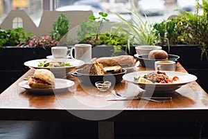 Full table of delicious and different dishes in cafe with cup of coffee in white dinnerware.