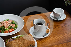 Full table of delicious and different dishes in cafe with cup of coffee in white dinnerware.