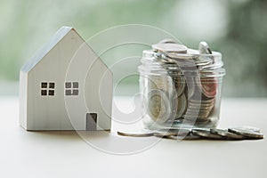 Full of Thai currency coin in saving jar with wood home on table with nature background