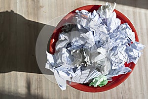 Full trash bin with crumpled paper scattered around