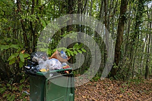 Full trash bin in the forest. Garbage pollution in the forest concept photo