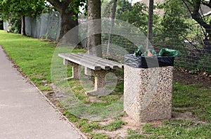Full trash can next to empty bench
