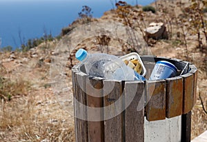 Full trash or litter bin with pet bottle, beer can and organic waste visibile showing pollution.