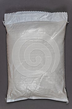 A full white bag against a gray background. Closed bag with food or other products. Top view. Copy space for text and design