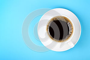 Full white cup of black coffee and saucer on blue
