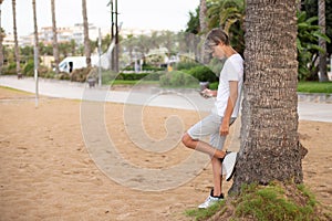 Fullbody handsome teenager boy using mobile phone outdoors in a park