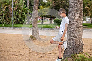 Fullbody handsome teenager boy using mobile phone outdoors in a park