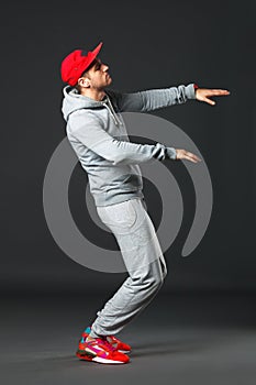 Fullbody portrait of young cool man dancing on dark background.