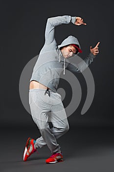 Fullbody portrait of young cool man dancing on dark background.