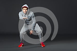 Fullbody portrait of young cool man dancing on dark background.