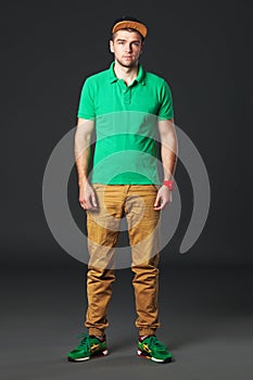 Fullbody portrait of young cool man standing on dark background