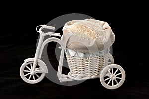 Fulled rice in straw rice bag on wooden tricycle on black background