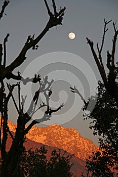 Fullmoon rise and vivid sunset on snowpeaked In photo