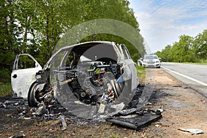 Fully burned car on roadside after collision with heavy truck