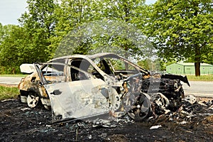Fully burned car on roadside after collision with heavy truck