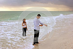 Fully clothed couple standing in ocean at sunset