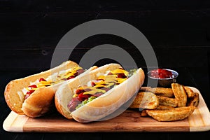 Fully loaded hot dogs and potato wedges on wooden board