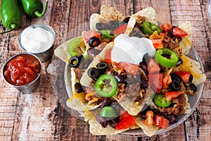 Fully loaded Mexican nacho chips on rustic wood background