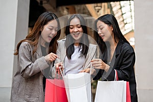 Fun Asian girls friends are enjoying their shopping day together, carrying their shopping bags