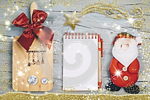 Fun background for the Christmas menu or recipes. Blank notebook, cutting board with utensils and miniature dishes and Santa Claus