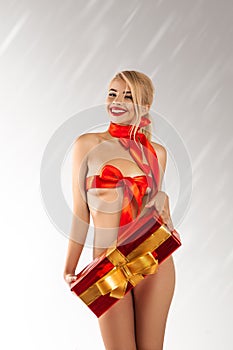 Fun beautiful girl with big gift and red ribbons on slim body