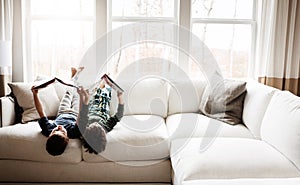 Fun children, bonding and reading books in education, learning or relax studying upside down on house living room or