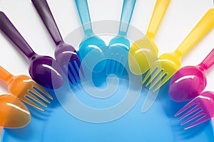 Fun colored background with plastic forks and spoons on the chil