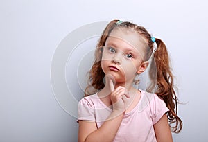 Fun confused kid girl thinking and looking serious about on blue