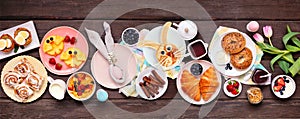 Fun Easter breakfast or brunch table scene. Above view on a dark wood banner background.