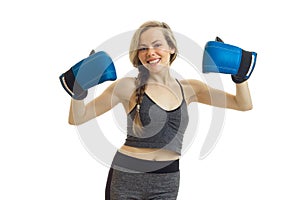 Fun energetic young blonde stands in sportswear and keeps hands in boxing gloves