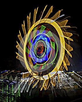 Fun fair Giant Colorful Ferris wheel spinning at night. Slow shutter zoom pan image of a rotating giant wheel at night