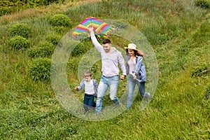 Fun family pastimes. Young parents with their kid flying kite together on green meadow