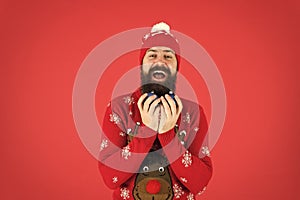 Fun festive activities. Hipster smiling cheerful bearded man wear winter sweater and hat hold balls red background. New