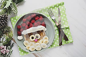 Fun food for kids. Christmas Santa pancake with raspberry and banana for children menu, top view with copy space