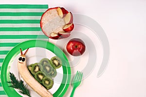 Fun food for kids. Cute smiling snail made from fruits banana, kiwi. Oatmeal porridge with apple slices. Healthy
