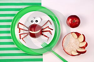 Fun food for kids. Cute smiling spider or crab made from red apple. Oatmeal porridge with apple slices. Healthy
