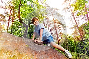 Fun in the forest boy climbs on small stone