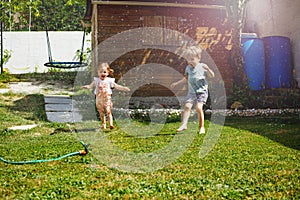 Fun in the garden - children run around water sprinkler