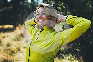 Fun girl exercising outdoors in sun summer day, smile fitness woman stretching exercises training outside in park. Happy sportswom