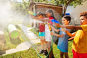 Fun kids with water guns fighting in the garden