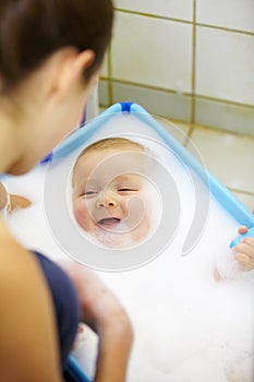 This is fun. Laughing baby boy getting a soapy foam bath from his mom.