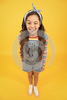 Fun lifestyle little girl long hair denim overalls, cheerful grimace concept